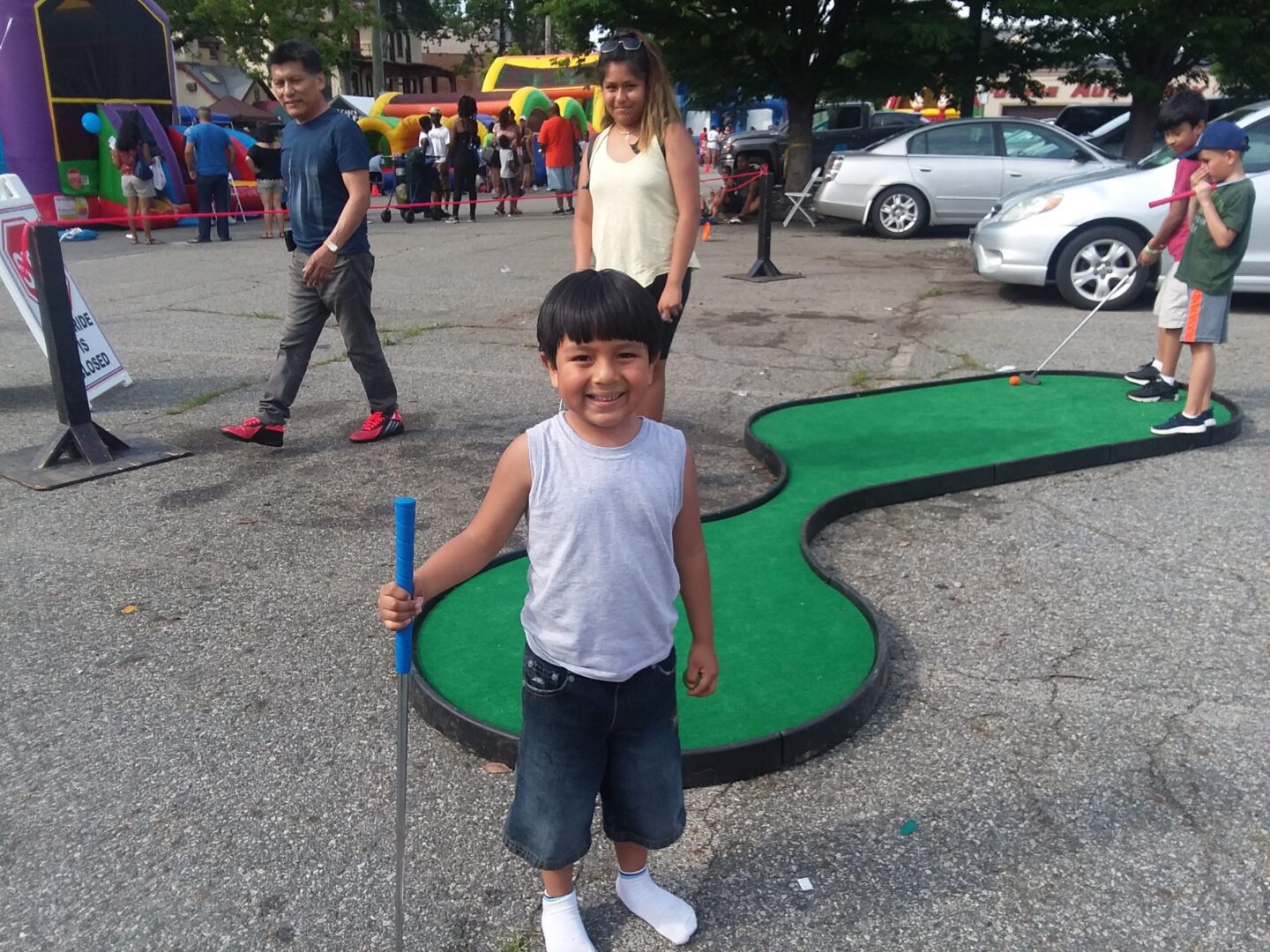 A young boy standing in front of a mini golf course.