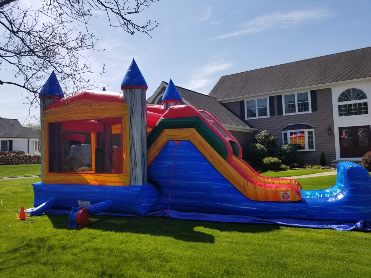 A castle bouncer with a slide in front of a house.
