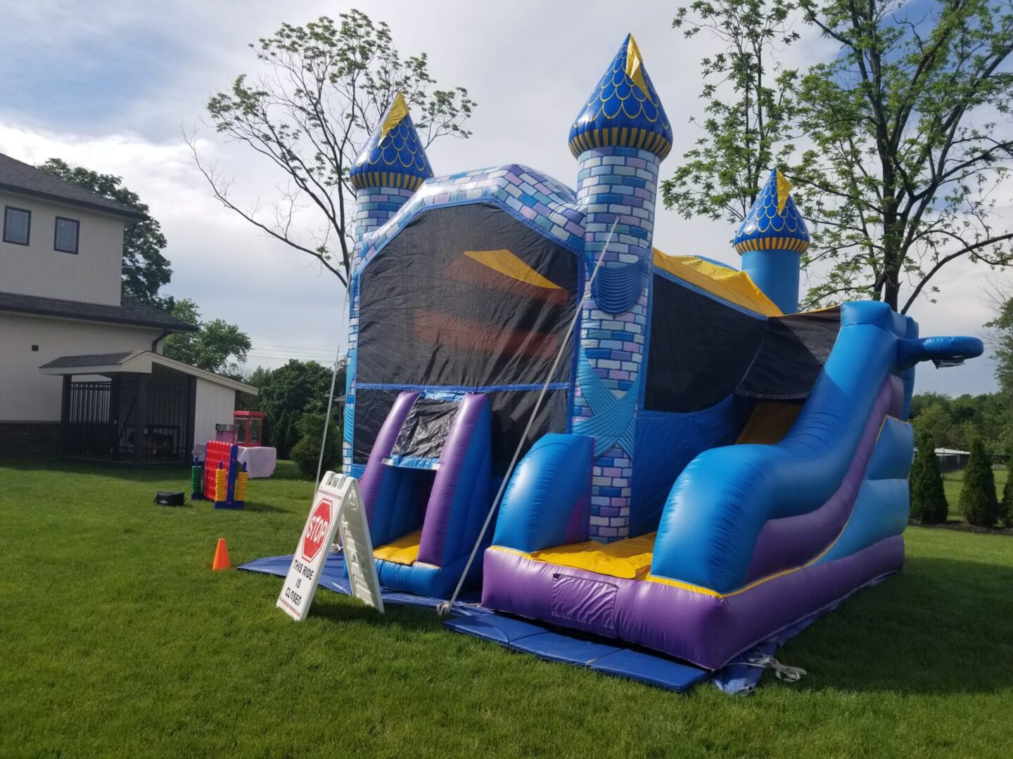 A bounce house with a castle and slide in the yard.