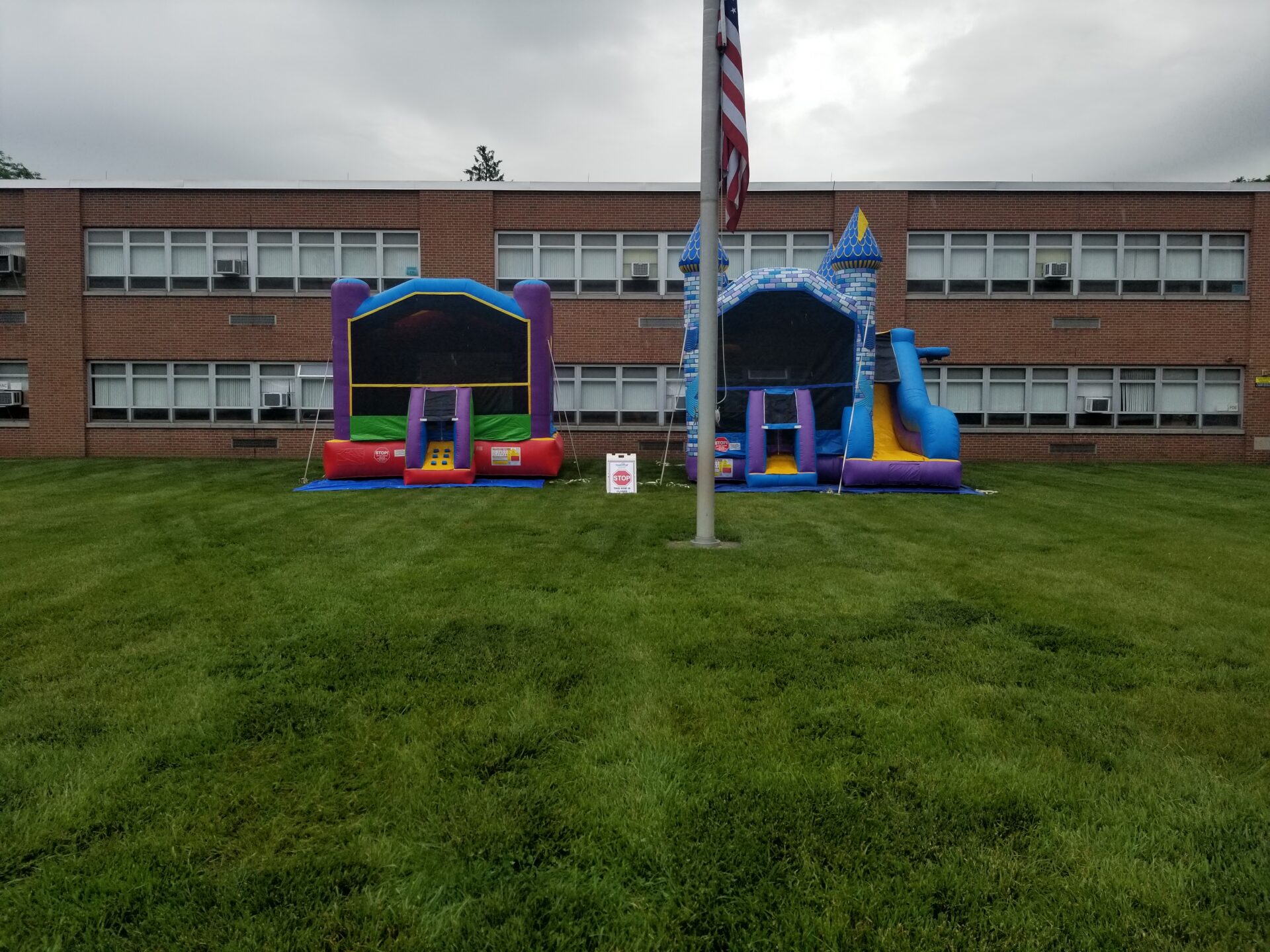 Two inflatable bouncers in front of a school building.