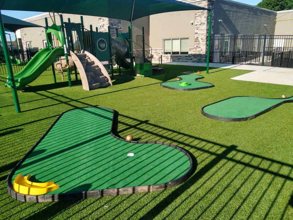 A green play area with several small golf holes.